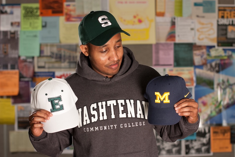 WCC student holding hats from different universities considering options.