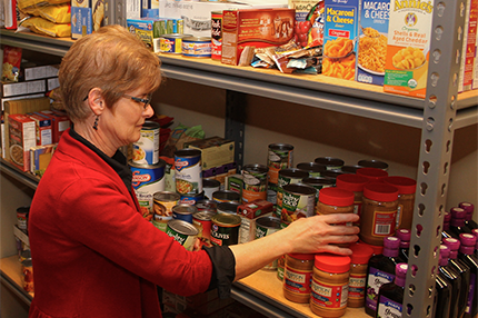 Carol Tinkle stocks the shelves of the WCC food pantry.