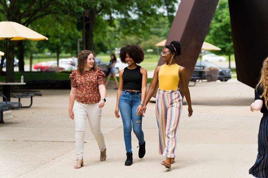 Trio of female students walk on campus.