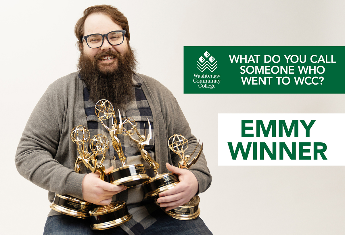 Photo of Joe Hallisy, white man with beard and glasses, holding gold award statues for Michigan Regional Emmy awards.