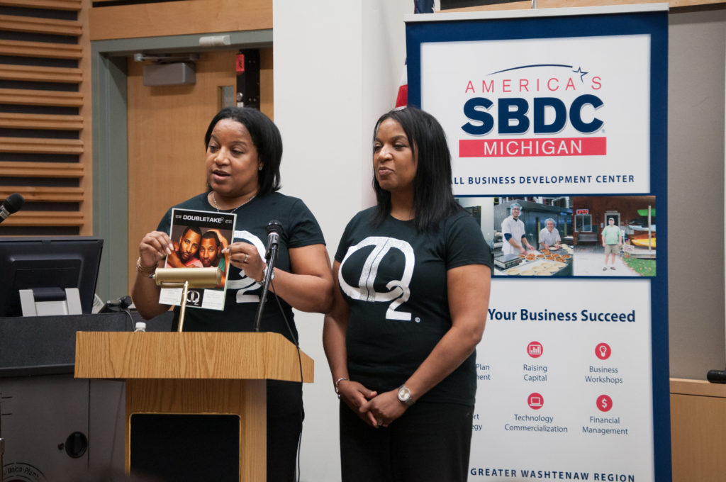 WCC employee Bernadette McClair holds up a mockup of Double Take 2, a magazine for twins she plans to publish with her twin sister, Antoinette (right). They were competing for investment money for their business at Pitch@WCC. (Photo by Jessica Bibee)