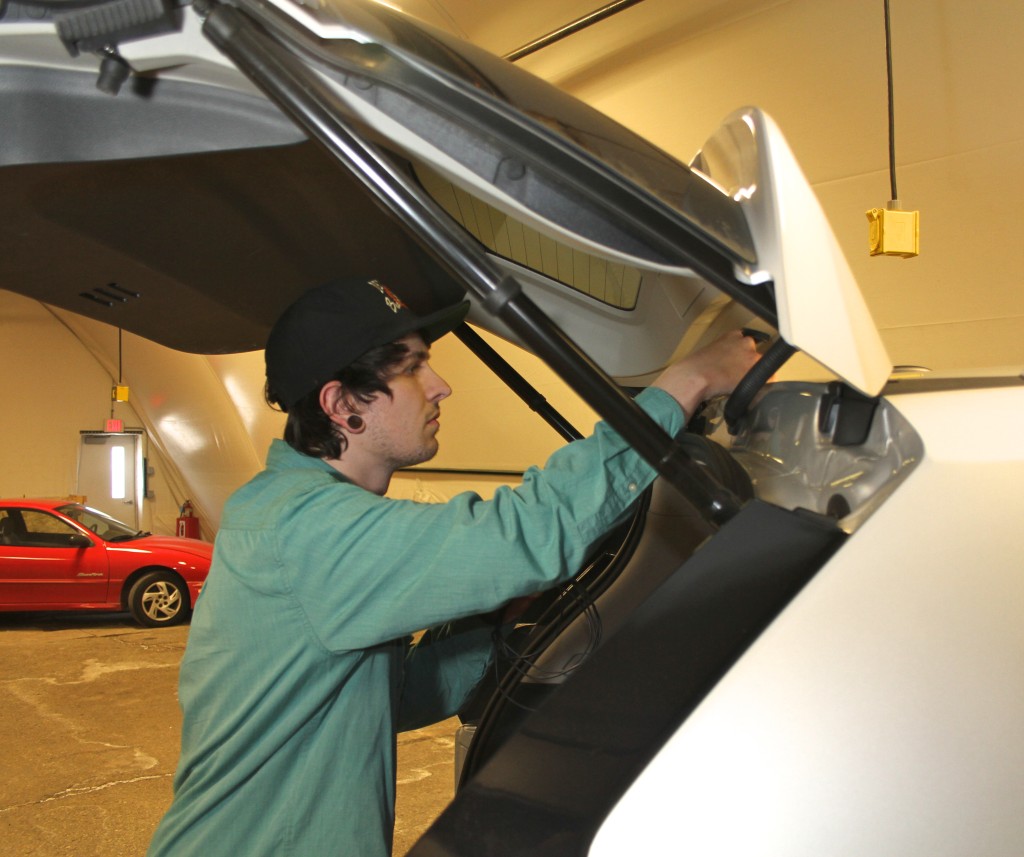 WCC student Calvin Tuttle installs Dedicated Short Range Communications technology into a car that is part of a U-M connected vehicle study. Photo by Lynn Monson