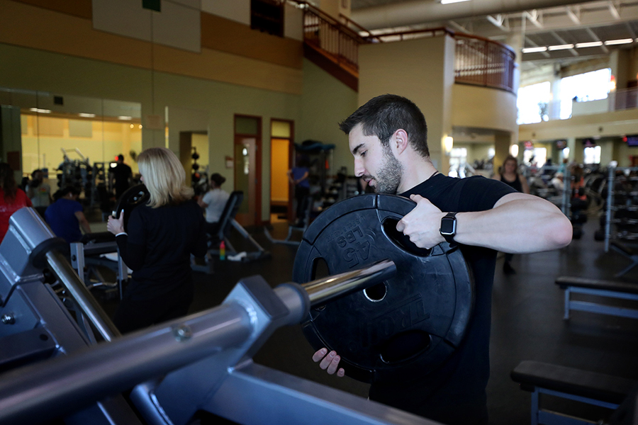 A fitness specialist sets up a leg press machine.