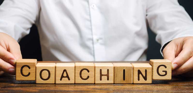 man laying blocks on table spelling coaching